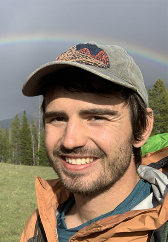 Young man with rainbow in background. 