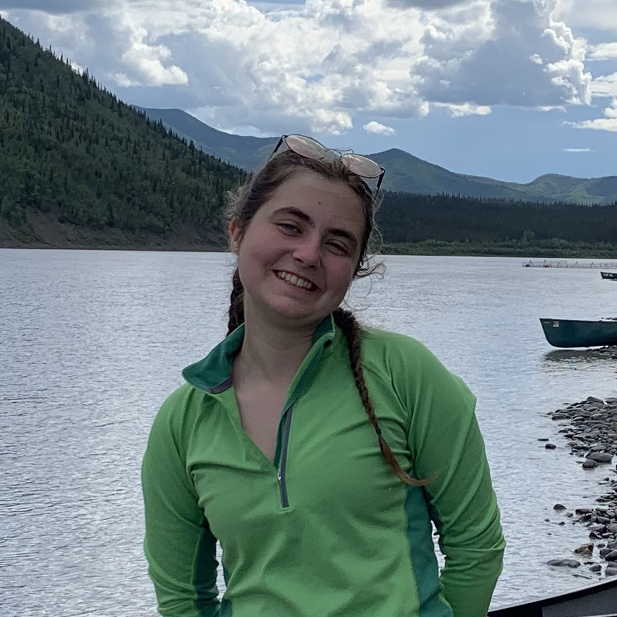 Chloe Crosson with lake and canoes in background.